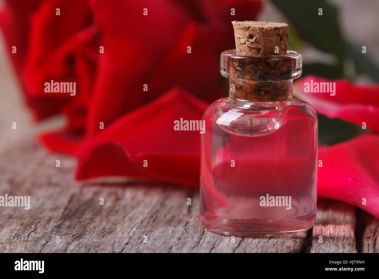 duftende Rosen-Wasser in einer Flasche auf einem Holztisch. Horizontale Nahaufnahme Stockfoto