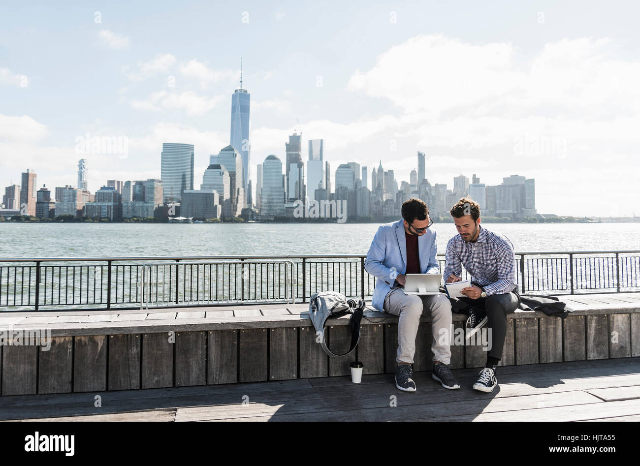 USA, zwei Geschäftsleute arbeiten bei New Jersey am Wasser mit Blick auf Manhattan Stockfoto