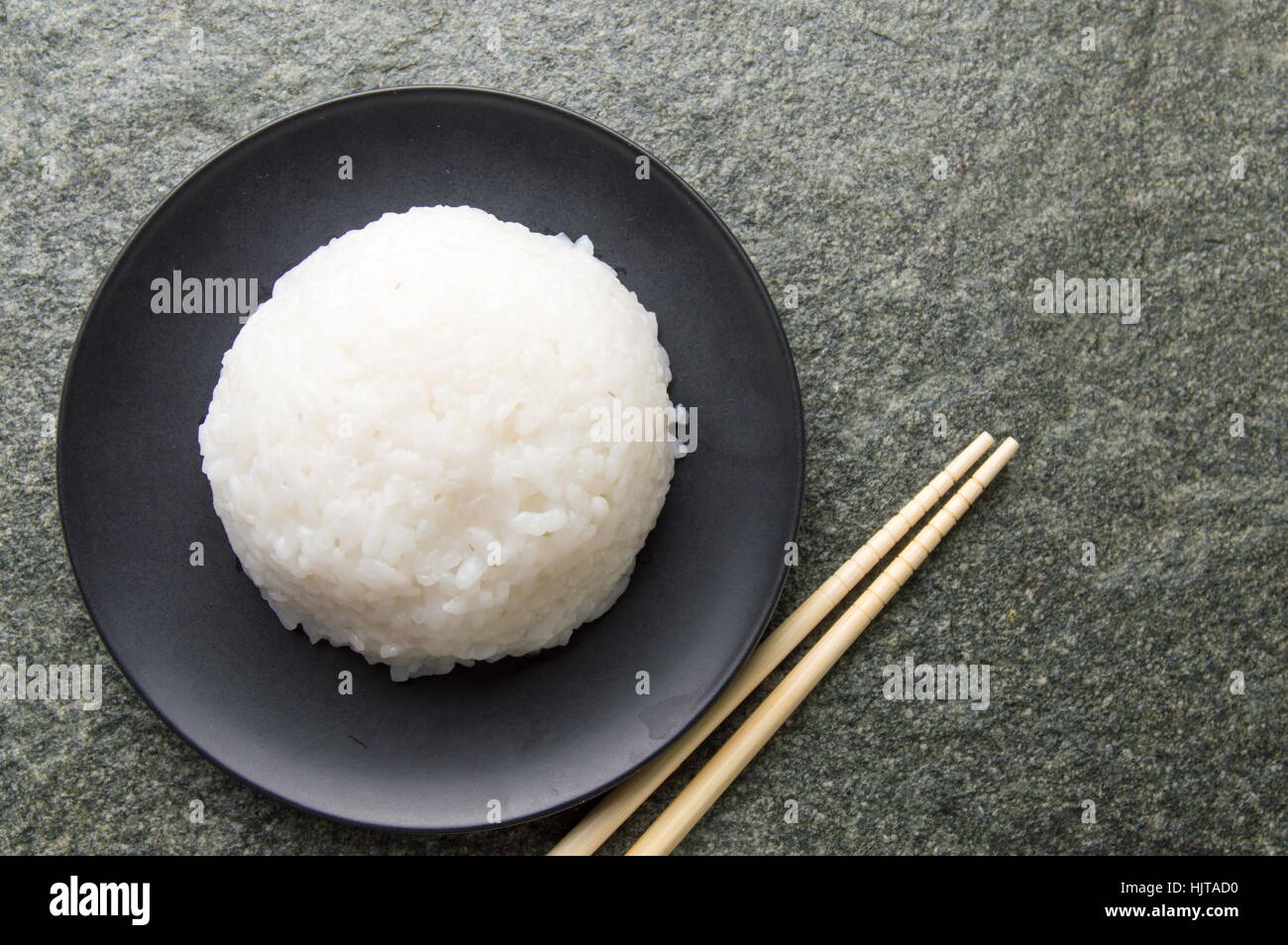Ball der Reis in eine schwarze Platte mit Stäbchen Stockfoto