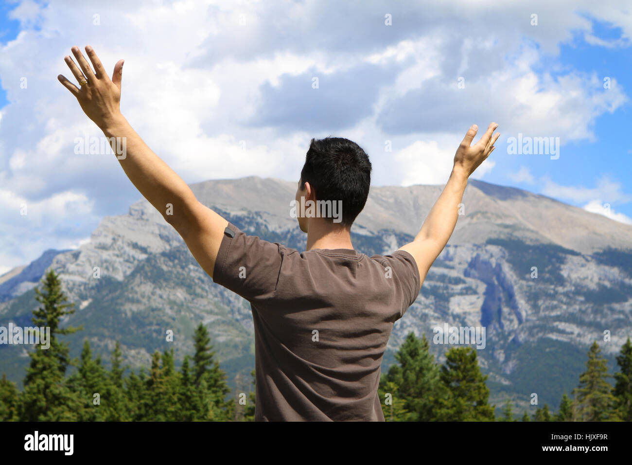 Junger Mann stehen draußen in den Bergen mit Arme hob Stockfoto