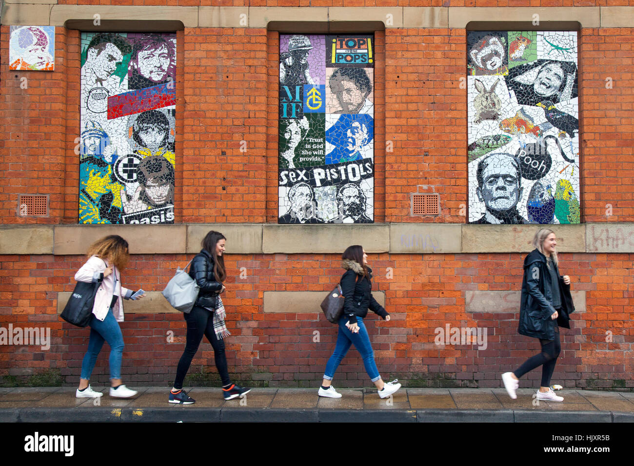 Menschen passieren Mosaiken und Gesichter berühmter Film- und Musikikonen in Tib Street, Northern Quarter, Manchester, Großbritannien Stockfoto