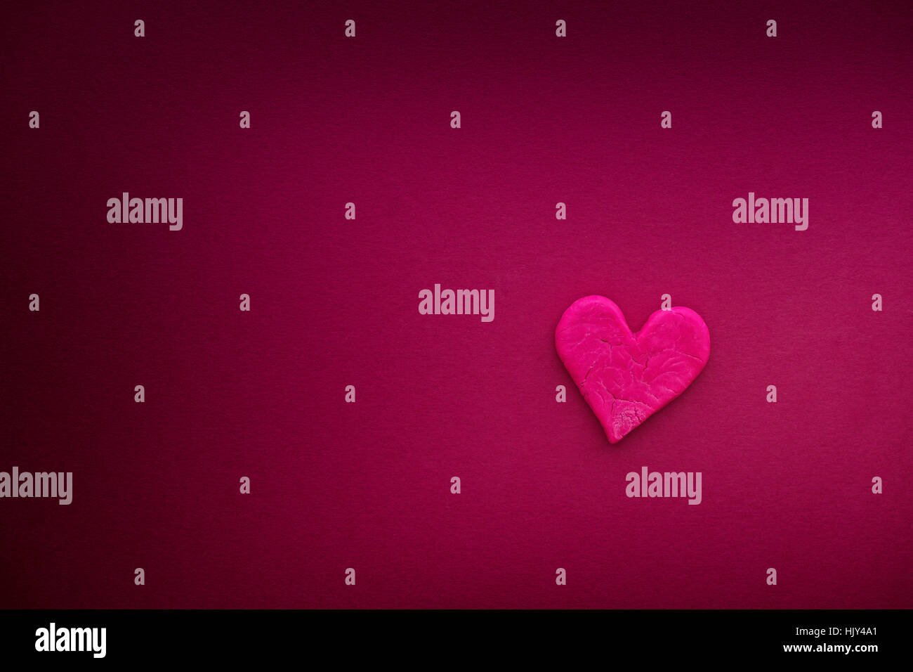 Rotes Herz mit kleinen Rissen auf heiße rosa Hintergrund. Hautnah. Stockfoto