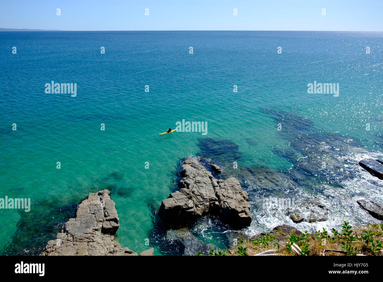 Blick von oben auf einer Klippe eine azurblaue Meer mit Felsvorsprüngen, und eine kleine Figur einer Person in einem Kajak, Noosa Nationalpark, Queensland, Australien Stockfoto
