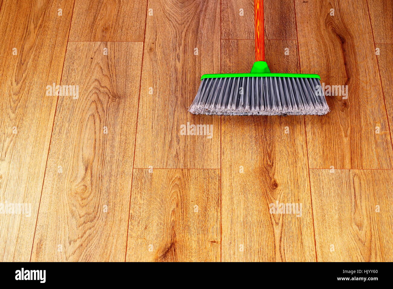 Reinigung den inneren Holzboden mit grünen Kunststoff Besen Stockfoto