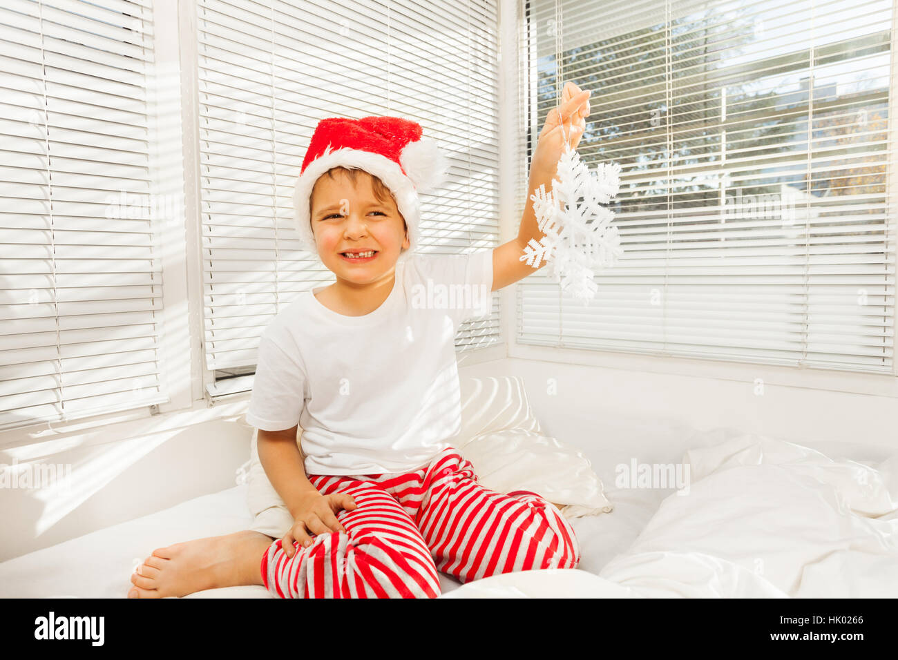 Junge sitzt auf seinem schlecht in Pyjamas und Weihnachtsmütze Stockfoto