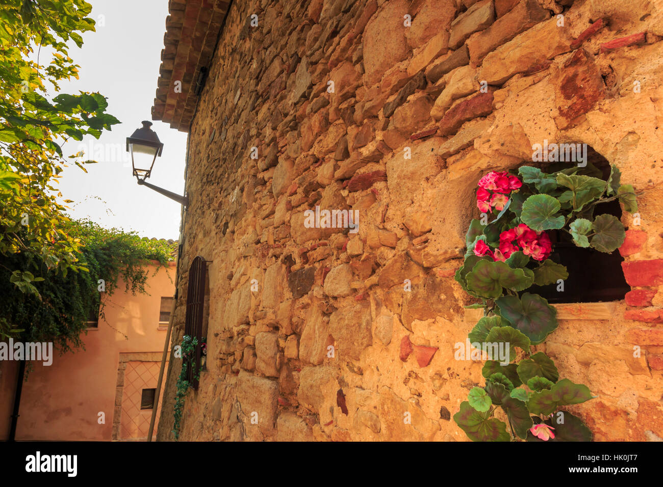 Wunderschöne mittelalterliche Dorf, Geranie mit rosa Blüten im alten Steinmauer, Peratallada, Baix Empordà, Girona, Katalonien, Spanien Stockfoto