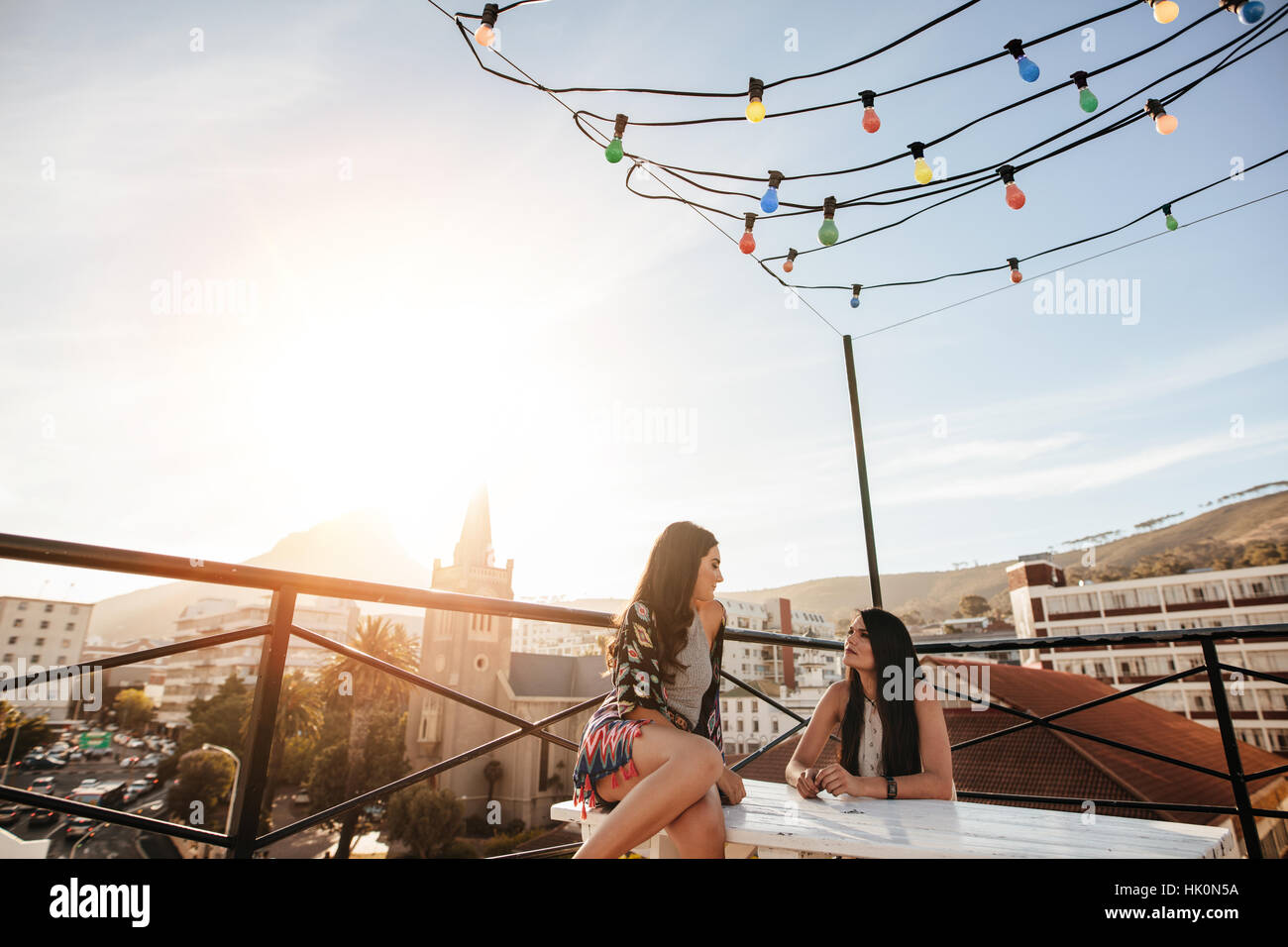 Zwei Freundinnen während Party auf dem Dach. Junge Frauen auf der Dachterrasse sitzen und reden. Stockfoto