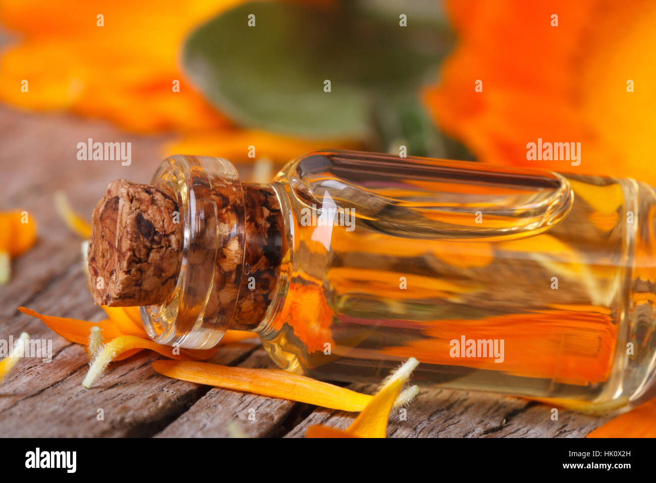 Calendula-Extrakt in einer Glasflasche und Blumen auf einem alten Tisch Makro horizontale Stockfoto