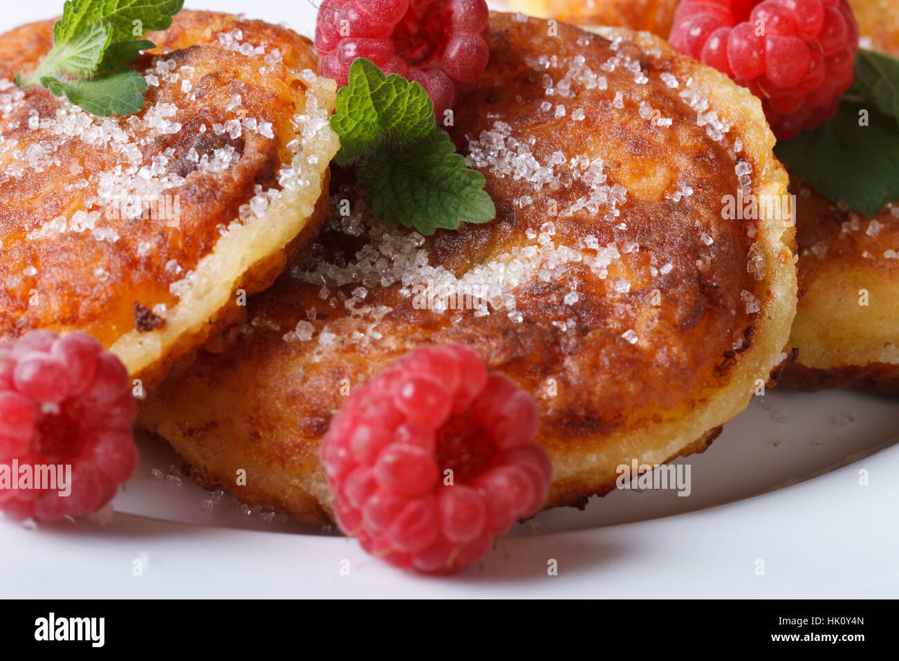Käse-Pfannkuchen mit frischen Himbeeren und Minze auf einem weißen Teller-Makro. horizontale Stockfoto