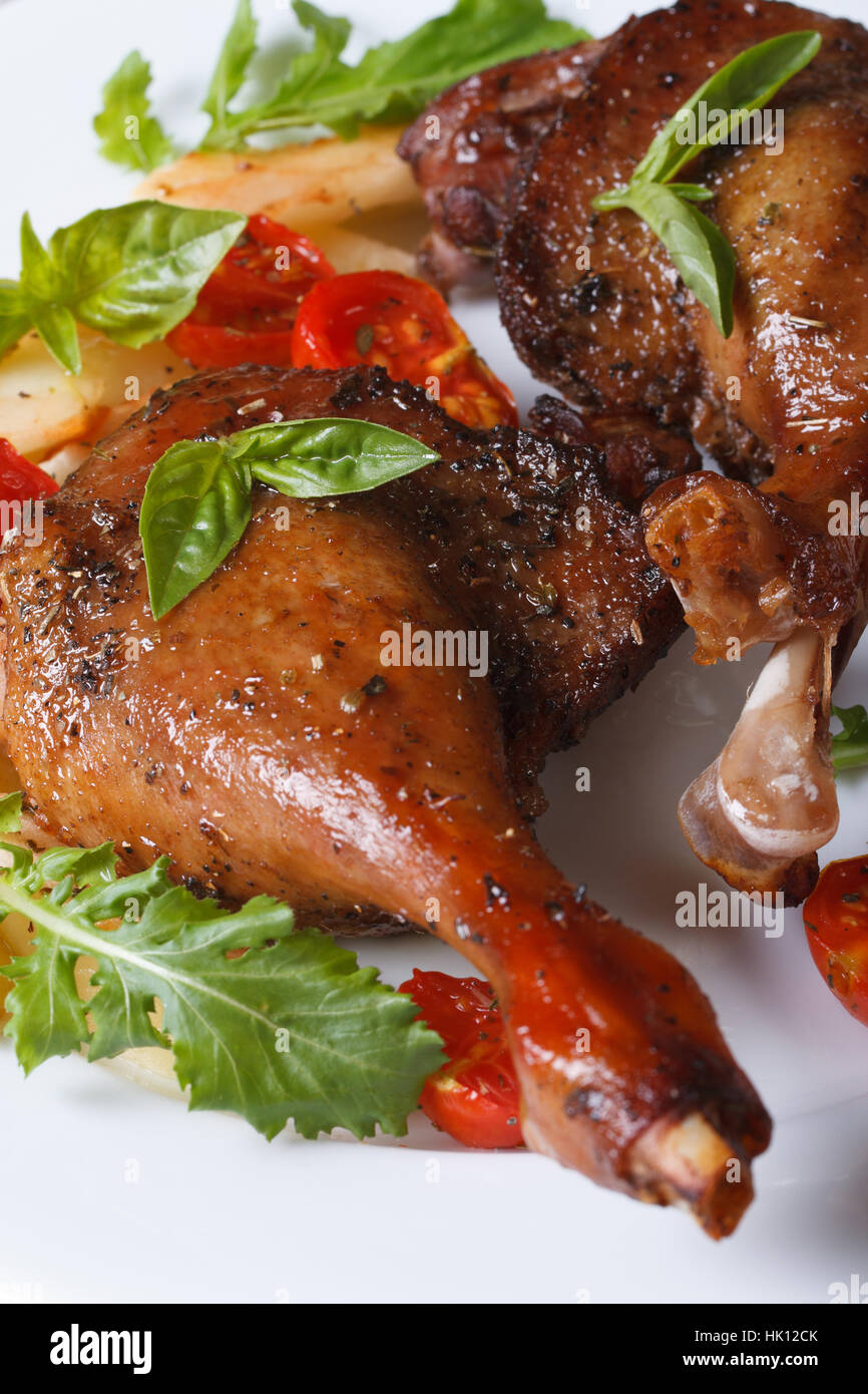Gebratene Entenkeulen mit Tomaten und Rucola weißer Teller Makro vertikalen Stockfoto