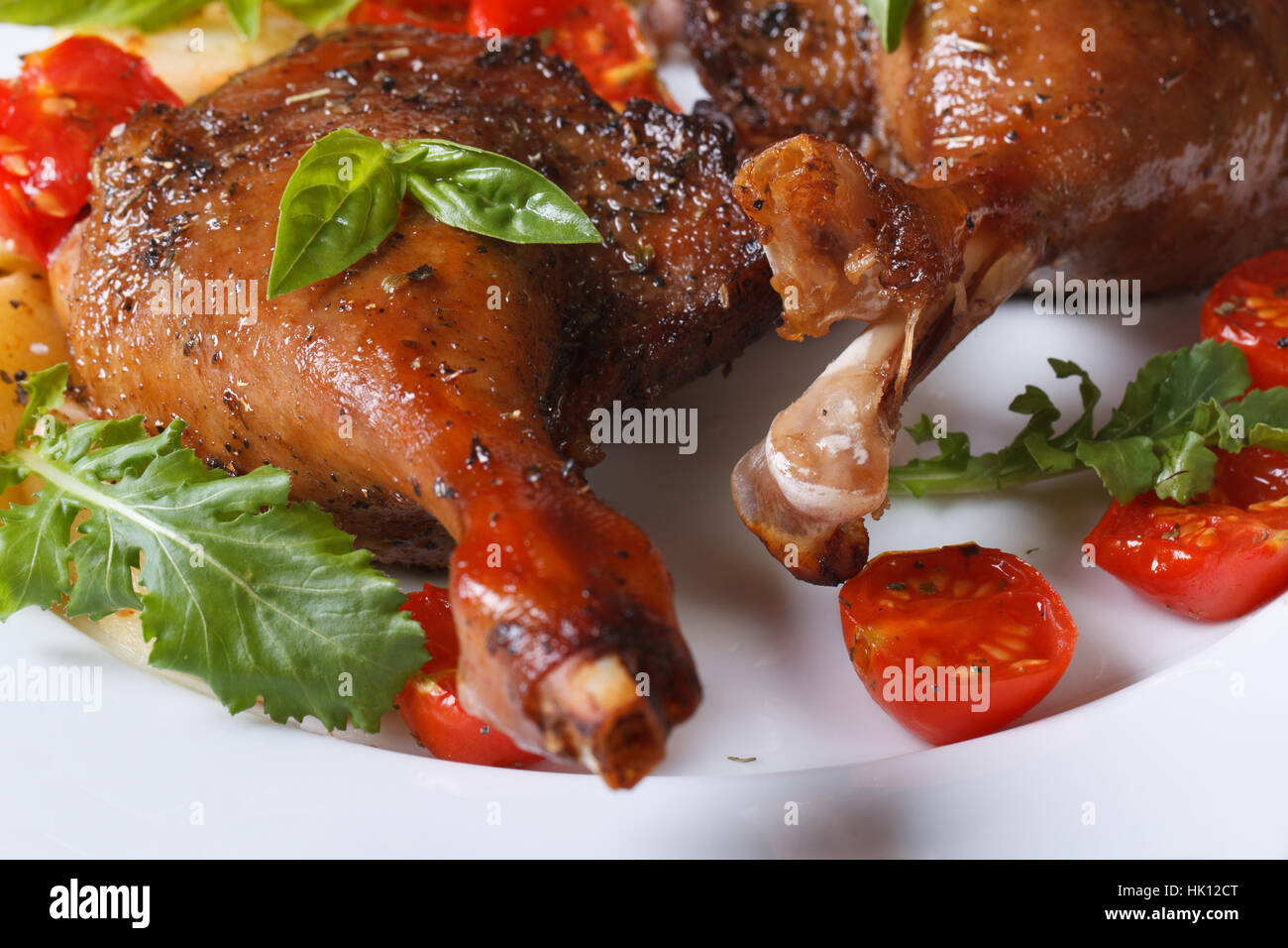 Gebratene Entenkeulen mit Tomaten und Rucola weißer Teller Makro horizontale Stockfoto