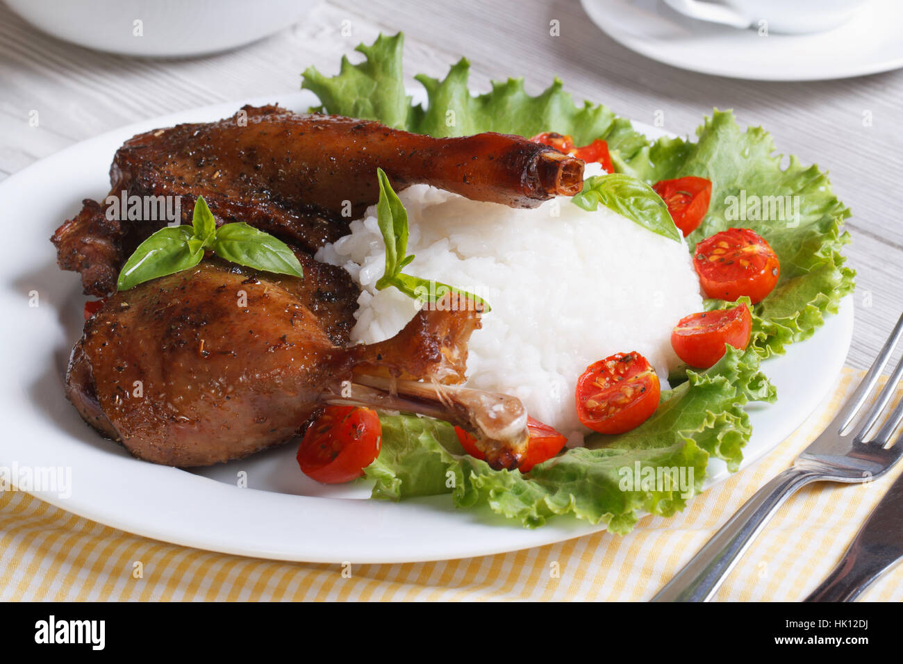 Gebratene Entenkeule mit Reis und Salat auf der horizontalen Platte Nahaufnahme. Stockfoto