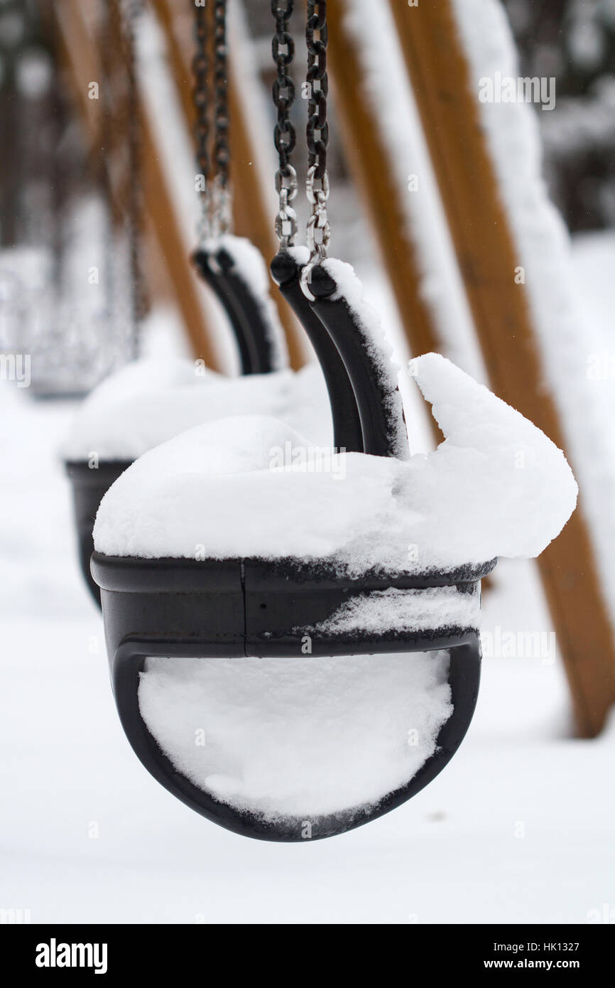 Vertikale perspektivische Ansicht des schwarzen Kunststoff Kind schwingt im verschneiten park Stockfoto