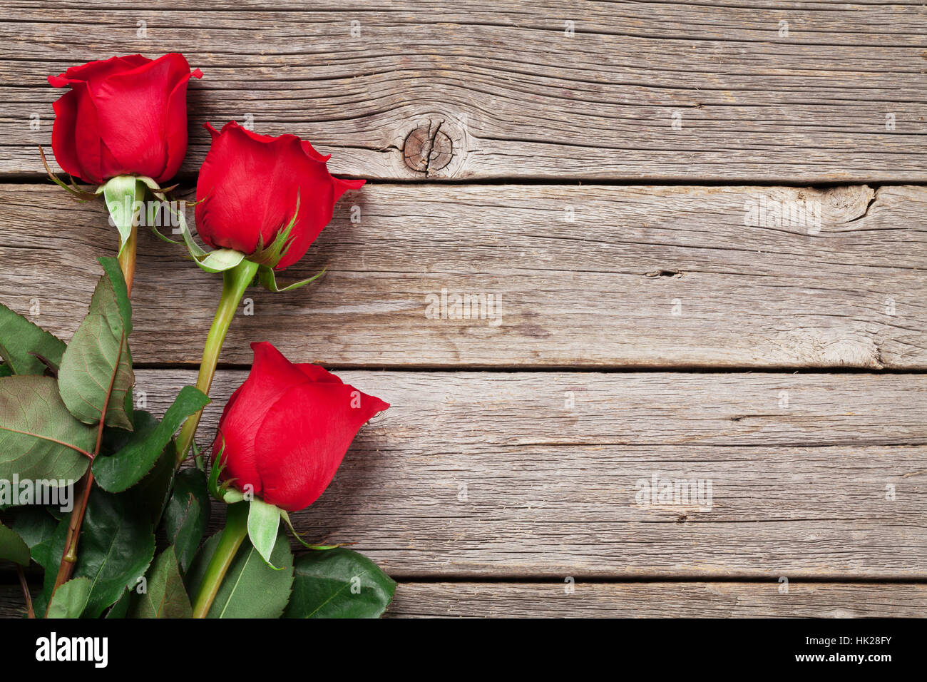 Valentinstag-Grußkarte. Rote Rosen auf Holztisch. Draufsicht mit Platz für Ihre Grüße Stockfoto