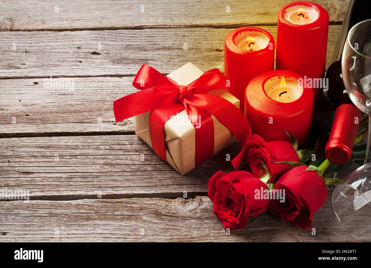 Valentinstag-Grußkarte. Rote Rosen-Blumen, Wein, Geschenk-Box und Kerzen auf Holztisch. Mit Platz für Ihre Grüße Stockfoto
