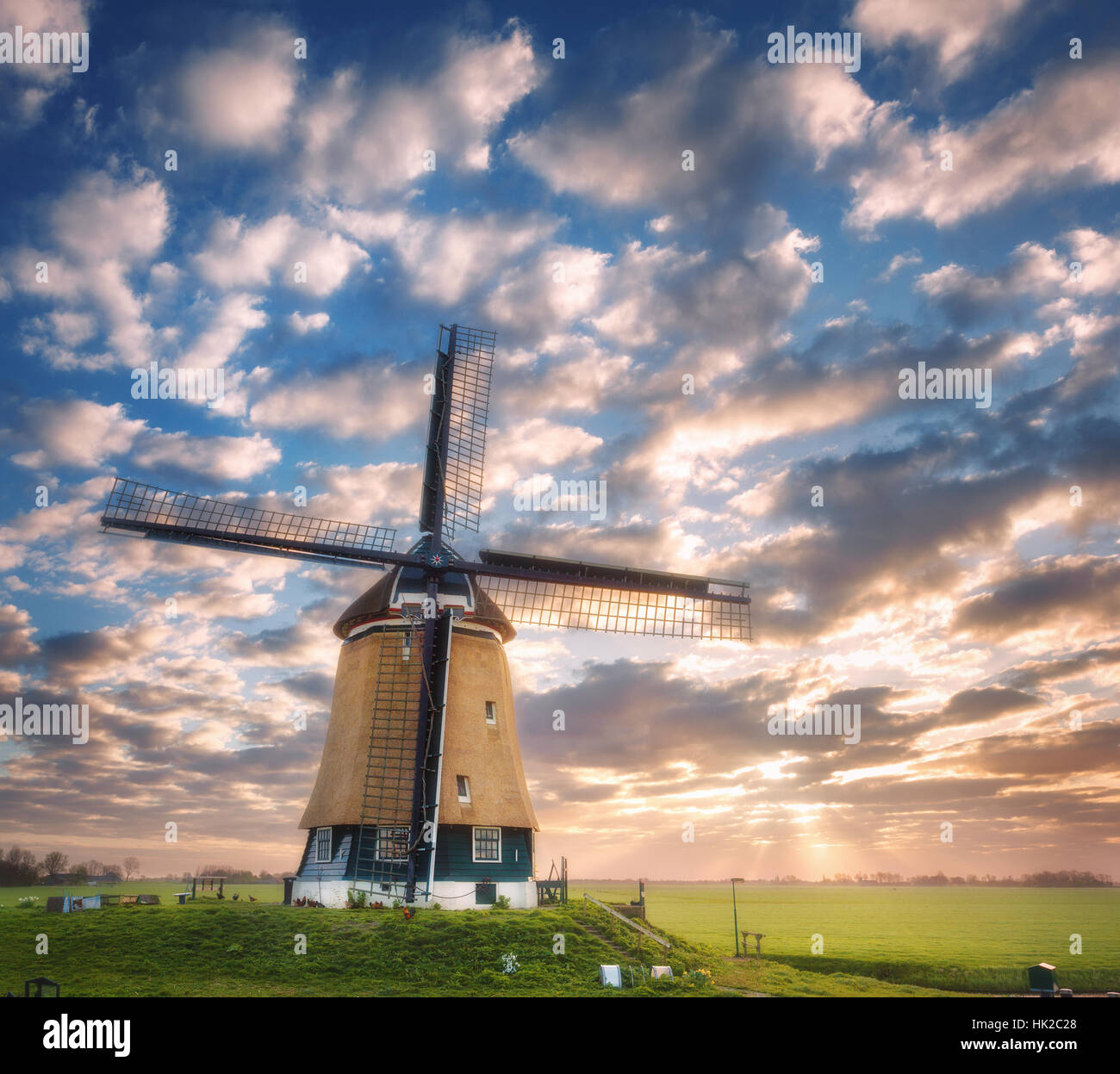 Windmühle bei Sonnenaufgang in Niederlande. Schöne alte holländische Windmühle gegen bunte Himmel mit Wolken. Frühlingslandschaft Stockfoto
