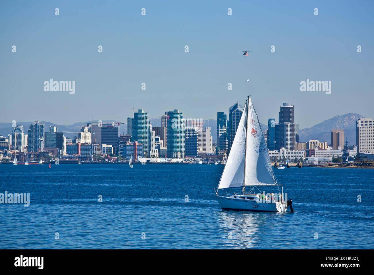 Downtown San Diego, Ca Skyline mit Segelboot in der Bucht von San Diego, Helikopter und Jet Flugzeug im Himmel oben. Stockfoto