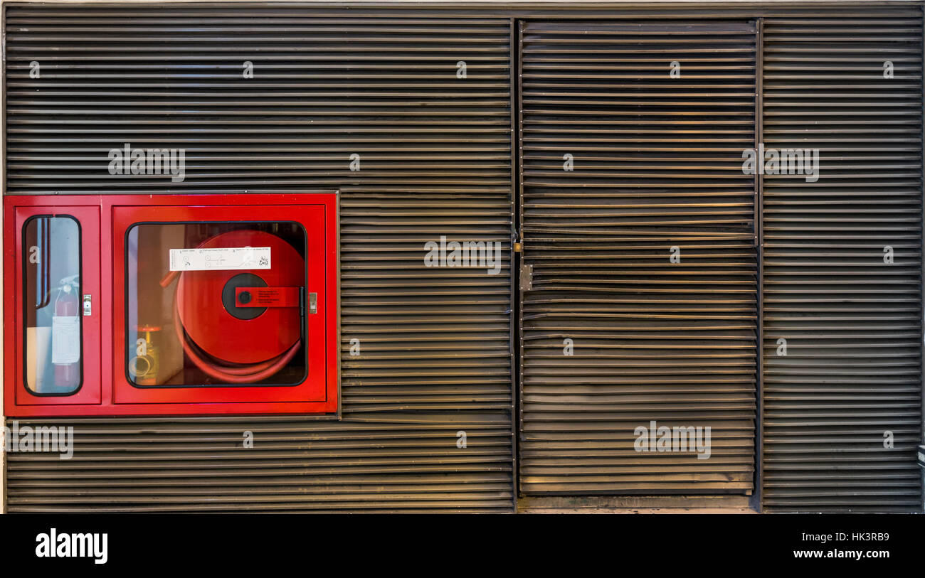 Feuerlöscher-Schrank in der Grunge-Metal Latten-Wand mit Textfreiraum Stockfoto