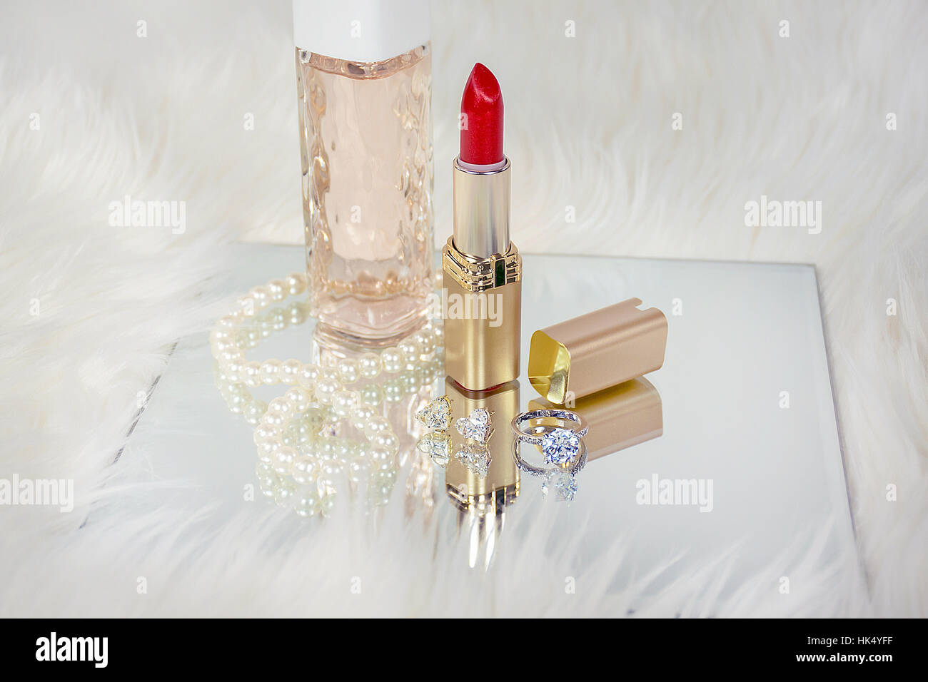 Roter Lippenstift in gold Röhrchen auf Spiegel mit Diamant und Perlenschmuck Stockfoto