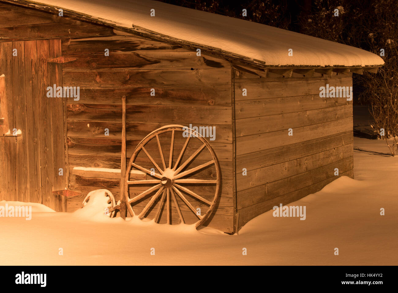 Verwitterte Holzschuppen mit Wagenräder und Schnee - Nacht, schräg, leichten Schnee Stockfoto