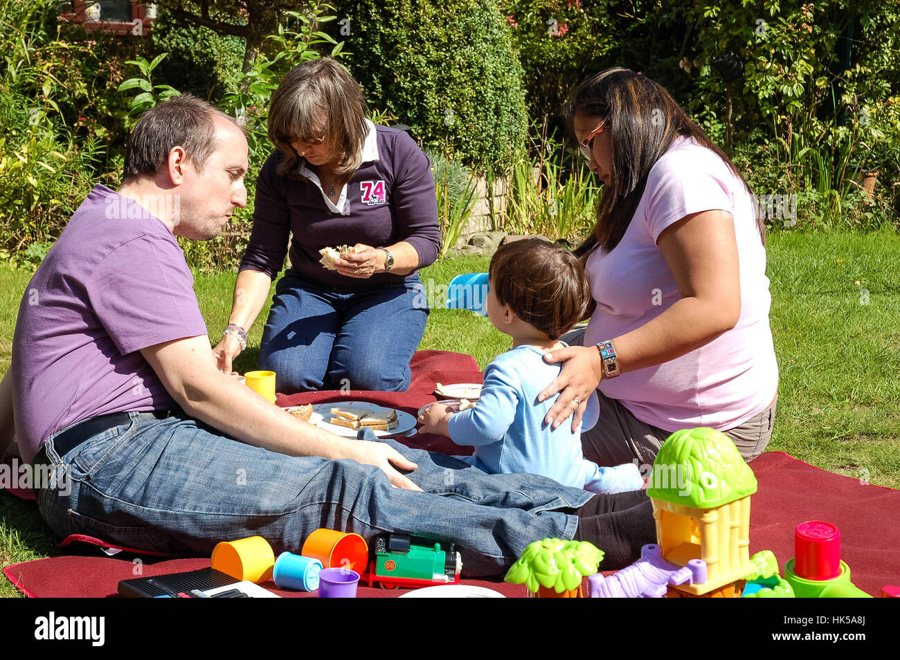 Eine junge Familie genießen Sie ein Picknick im Garten hinter dem Haus. Stockfoto