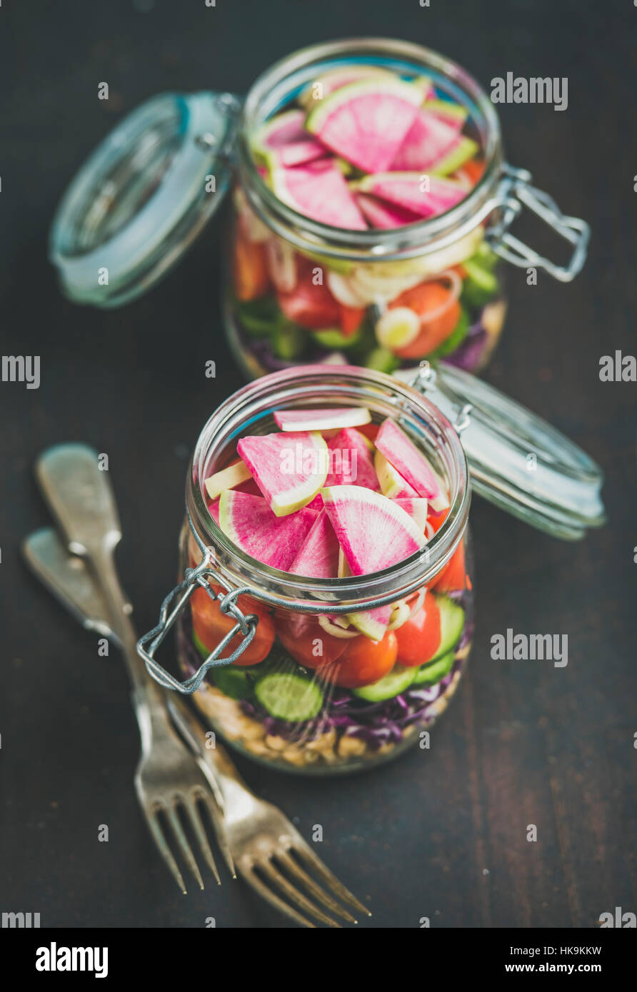 Gesundes Mittagessen zum Mitnehmen-Gläser. Gemüse und Kichererbsen sprießen vegane Salat in Gläsern über verbrannten Holz dunkel, selektiven Fokus. Sauber Essen Stockfoto