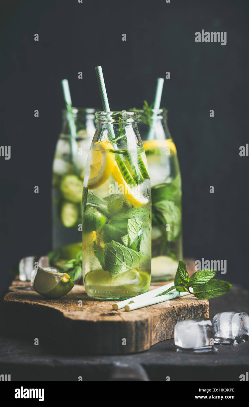 Zitrusfrüchten und Kräutern hineingegossen Sassi Wasser für Detox, gesundes Essen oder eine Diät in Glasflaschen mit Strohhalmen, dunklen Hintergrund, selektiven Fokus. Sauber Stockfoto