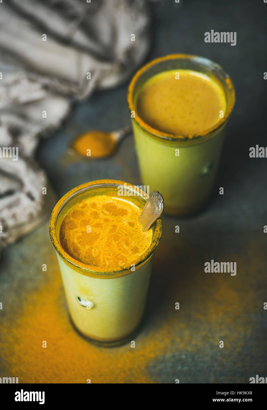 Goldene Milch mit Kurkuma-Pulver in Gläsern auf dunklem Hintergrund. Gesundheit und Energie fördernde, Grippe Heilmittel, natürliche kalten Getränk zu kämpfen. Sauber, Essen, d Stockfoto