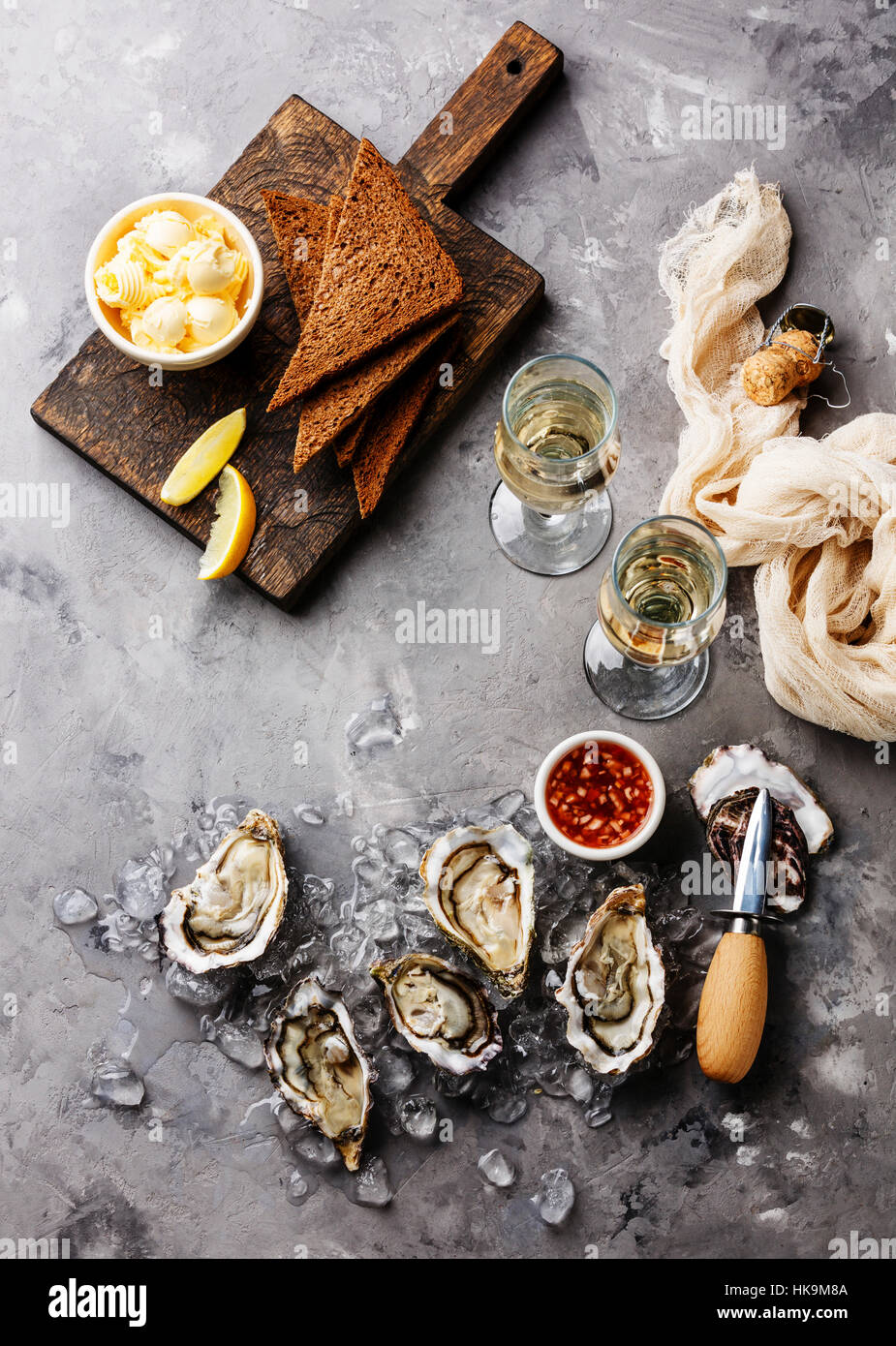 Geöffnete Austern mit Brot und Butter und Champagner auf grauem Beton Textur Hintergrund Stockfoto