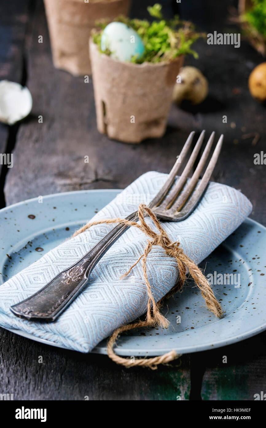 Tabelle Einstellung Dekor bunte Ostern Wachteleier mit Kirsche Frühlingsblumen, Moos im Garten Töpfe leeren Tellern, Besteck über alte Holz Hintergrund. Dunklen r Stockfoto