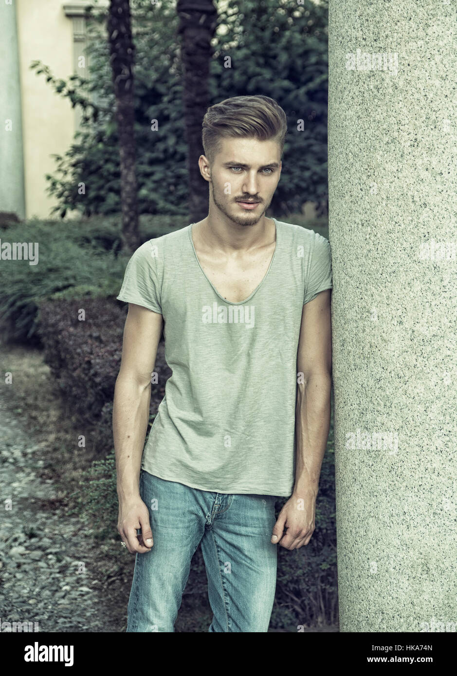 Attraktive blaue Augen, blonde junge Mann gegen Steinsäule Stockfoto