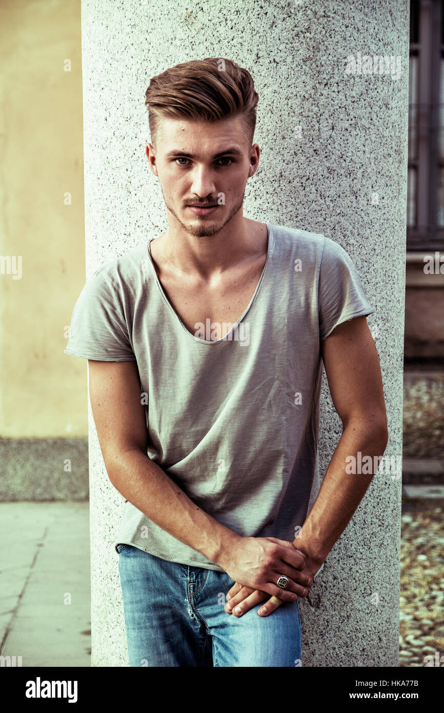 Attraktive blaue Augen, blonde junge Mann gegen Steinsäule Stockfoto