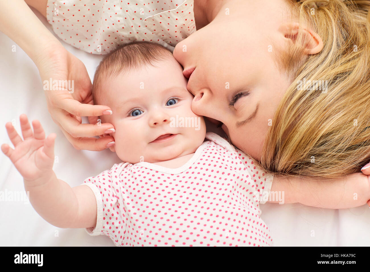 Mama küsst Baby auf dem Bett Stockfoto