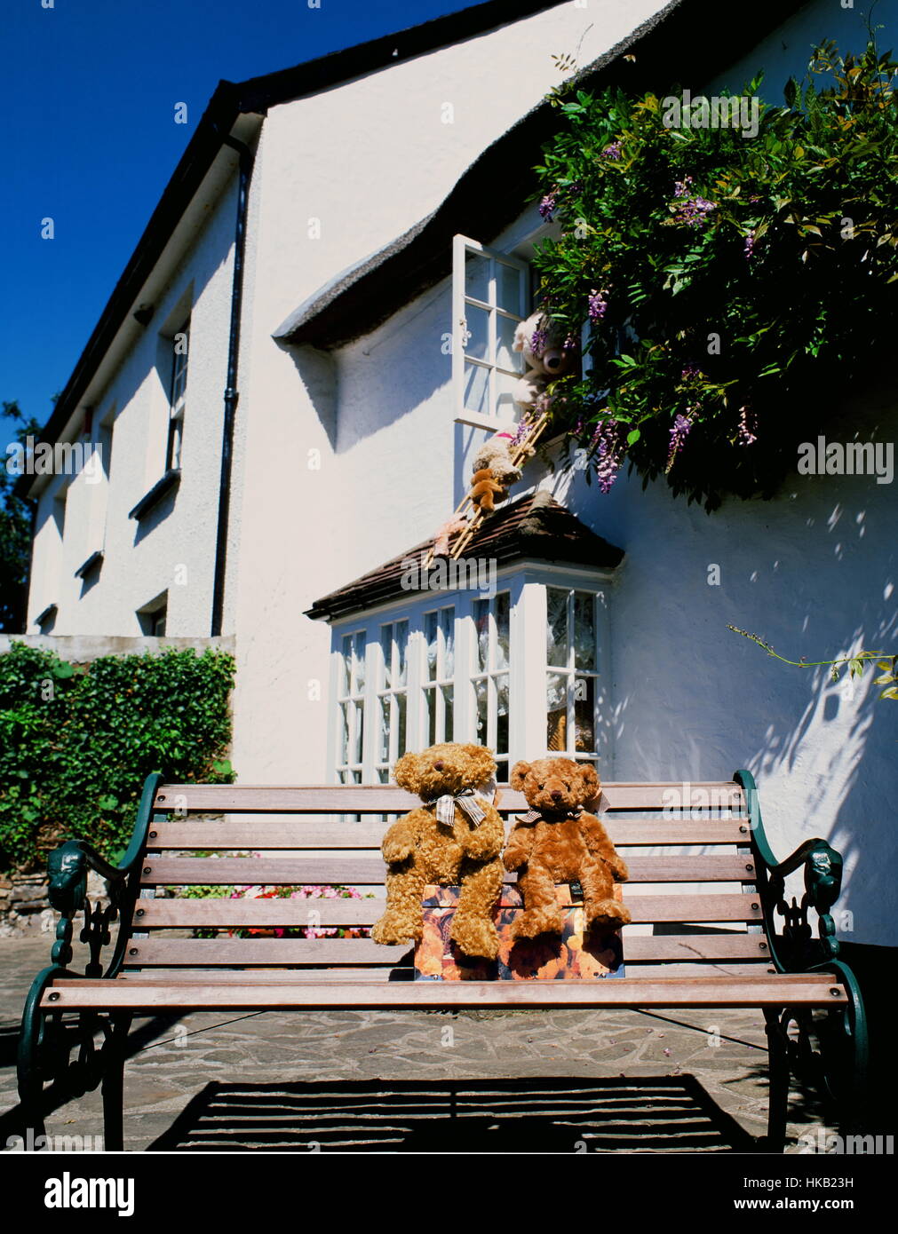 Teddybären auf einer Bank sitzen und klettern aus dem oberen Fenster von einer Hütte Stockfoto