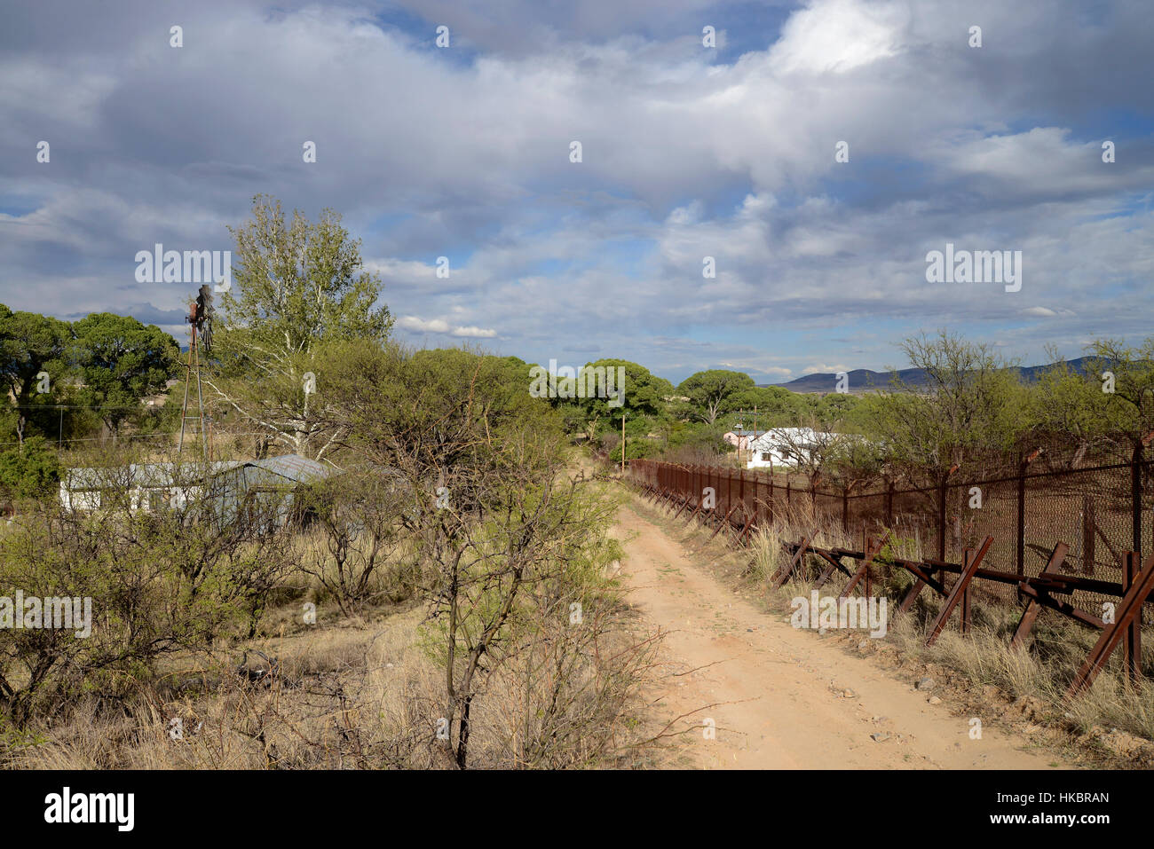 Eine Metallwand trennt Häuser und die mexikanische Grenze zu Sonora, Mexiko, definiert, wie gesehen von Lochiel, Arizona, USA. Stockfoto
