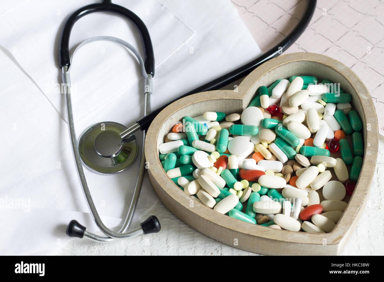 Stethoskop und Pillen im Herzen gegen Kardiogramm medizinisches Konzept Stockfoto