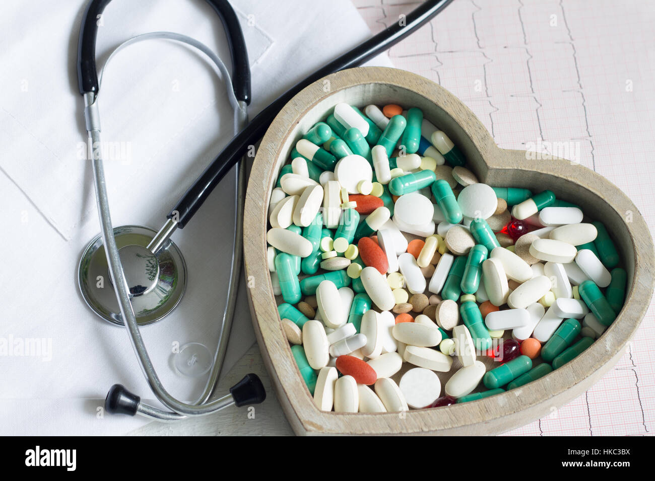 Stethoskop und Pillen im Herzen gegen Kardiogramm medizinisches Konzept Stockfoto