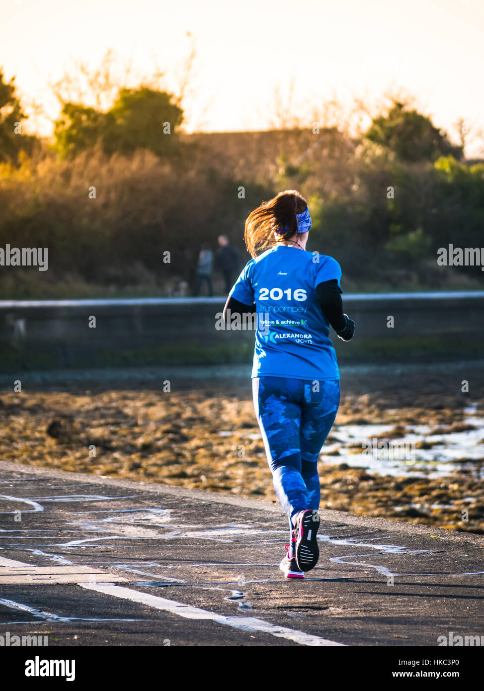 Eine einsame Frau nimmt einen Morgenlauf entlang der Küste von Portsmouth Stockfoto