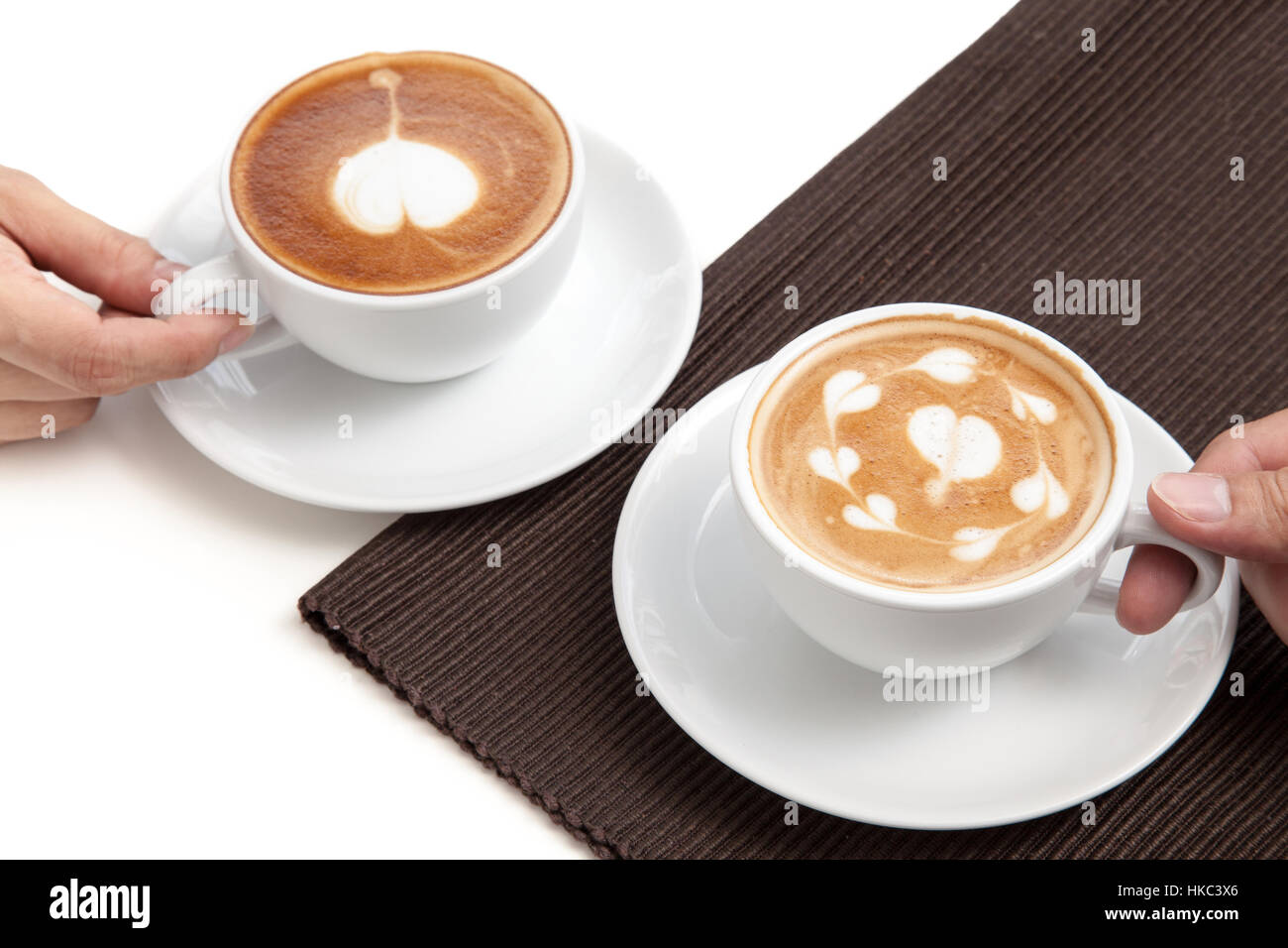 Zwei Kaffeetassen Latte Art Herzform platzieren auf Serviette auf weißen Hintergrund isoliert Stockfoto