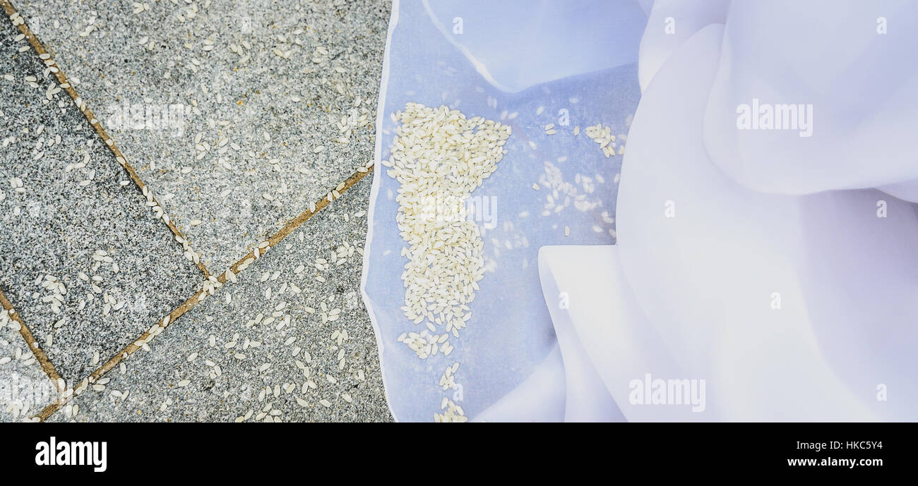 Detail der Braut Brautkleid mit Reis auf dem Boden. Pflaster voller Reis nach einer Trauung. Stockfoto
