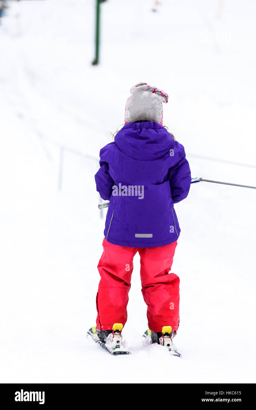 Kleines Mädchen lernt Skifahren im Skigebiet. Kind ist Ski Baby Aufzug Förderband Skifahren zum ersten Mal verwendet. Aktive Kinder sind glücklich. Stockfoto