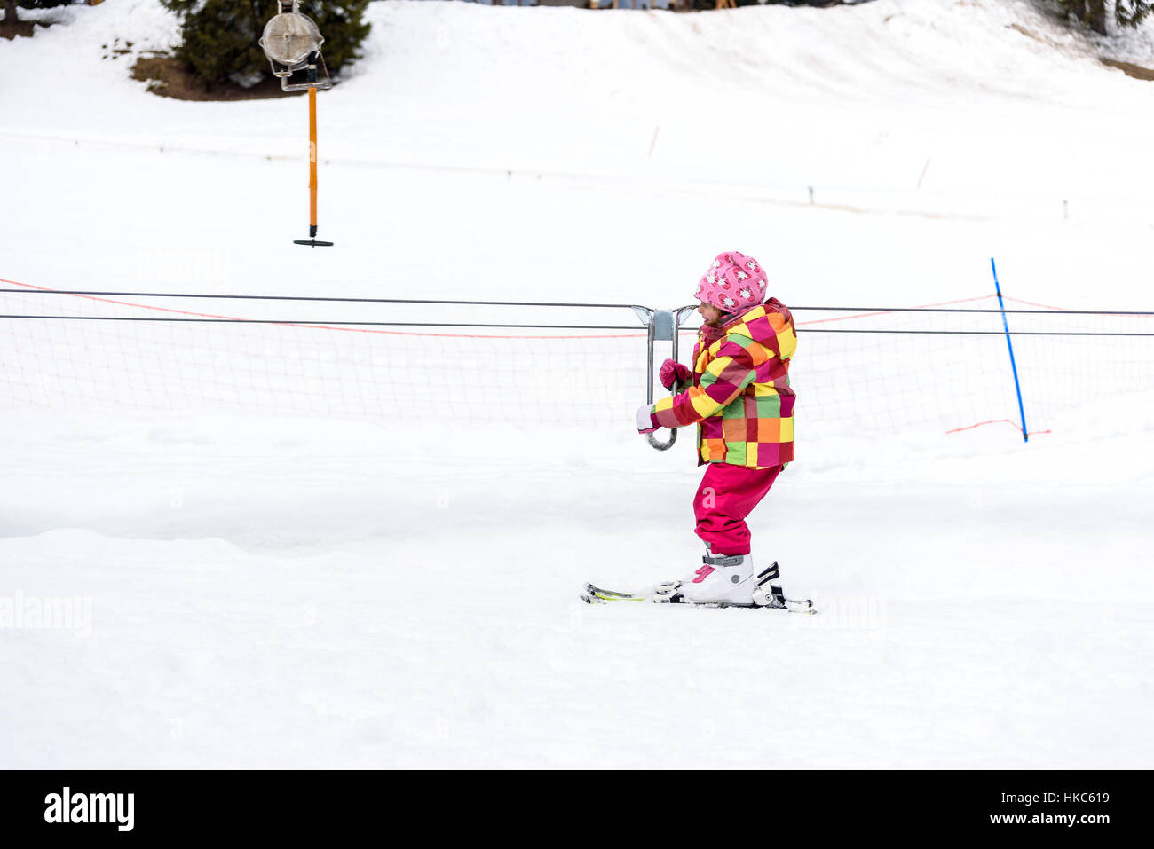 Kleines Mädchen lernt Skifahren im Skigebiet. Kind ist Ski Baby Aufzug Förderband Skifahren zum ersten Mal verwendet. Aktive Kinder sind glücklich. Stockfoto