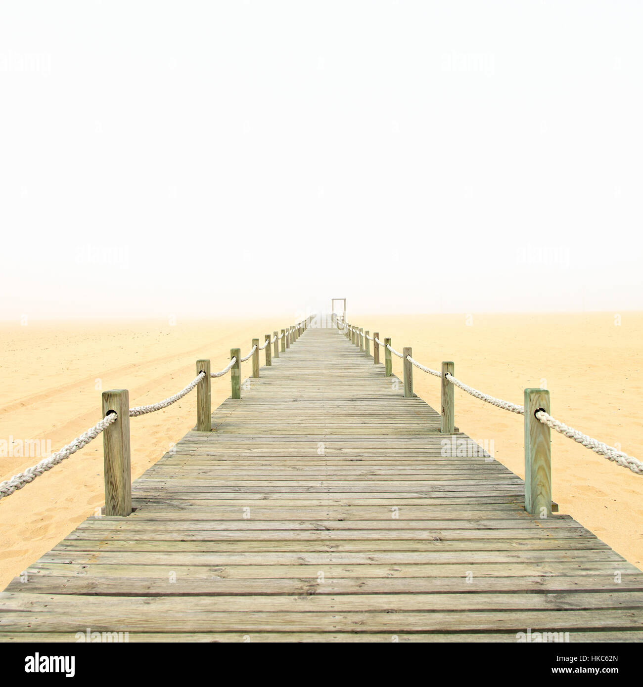 Holzsteg an einem nebligen Sandstrand. Figueira da Foz, Portugal, Europa. Stockfoto