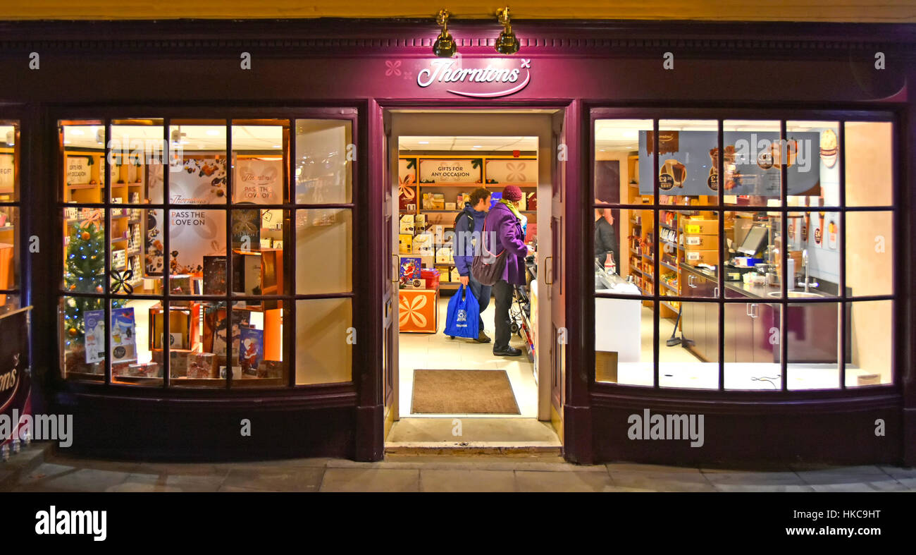 Kunden im Einzelhandel Winternachmittag Einkaufen in einem schottischen Thorntons Schokoladengeschäft Bogen fronted Windows offene Tür Edinburgh Schottland UK Stockfoto
