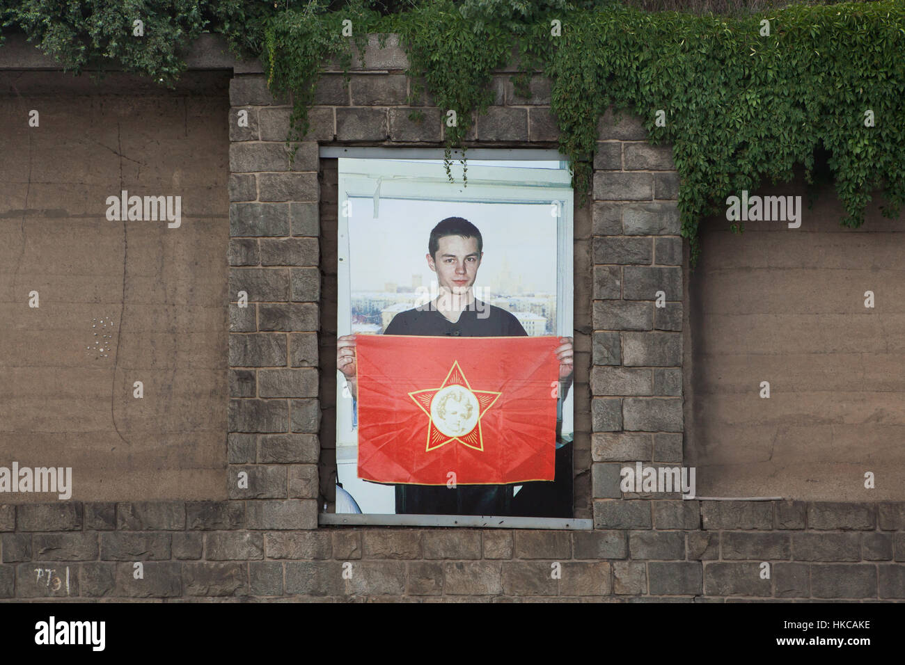 Foto von russischen Fotografen Slava Mogutin aus der Serie Lost Boys. Liebesgrüße aus Moskau in seiner Ausstellung in der Galerie Artwall in Prag, Tschechische Republik außerhalb angezeigt. Ein Junge auf dem Foto hält eine rote Fahne der sowjetischen Jugendorganisation des kleinen Octobrists mit dem fünfzackigen Stern Abzeichen mit dem Porträt von Vladimir Lenin in seiner Kindheit. Stockfoto