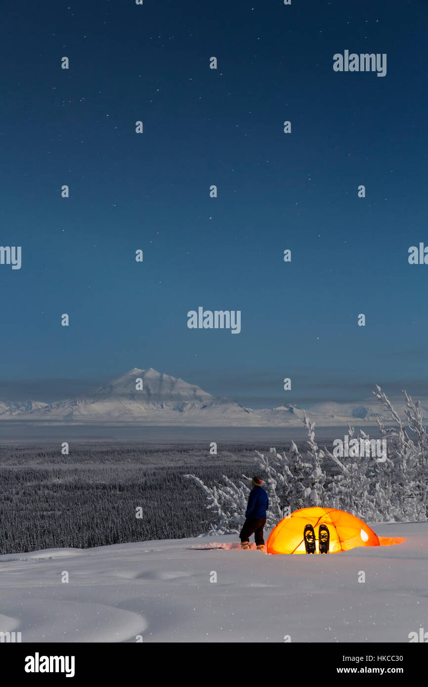 Mann sieht Mount Trommel und der Copper River Valley mit einem Zelt und Schneeschuhe im Vordergrund, Yunan Alaska, USA, Winter Stockfoto