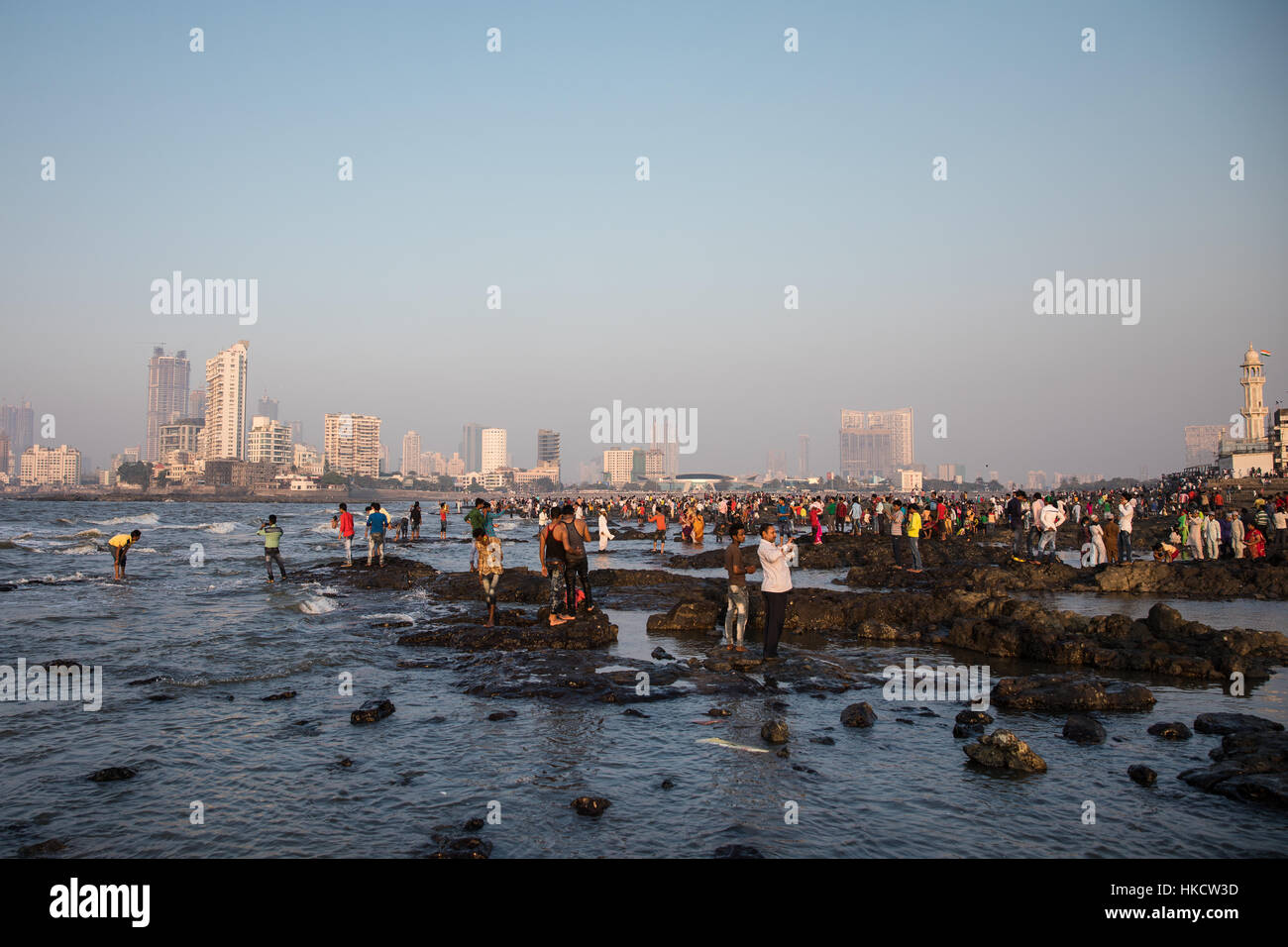 Menschen spielen auf die Felsen, die umgeben von Haji Ali Dargah, einer islamischen Moschee und Grab in Mumbai (Bombay), Indien. Stockfoto