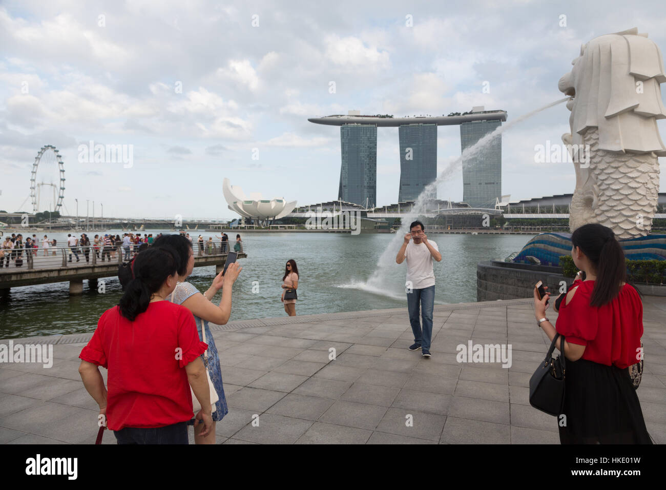 Singapur, Singapur - 22. Februar 2016: Touristen fotografieren vor der Marina Sands Gebäude und der Merlion Statue in der Bucht von Singapur Stockfoto