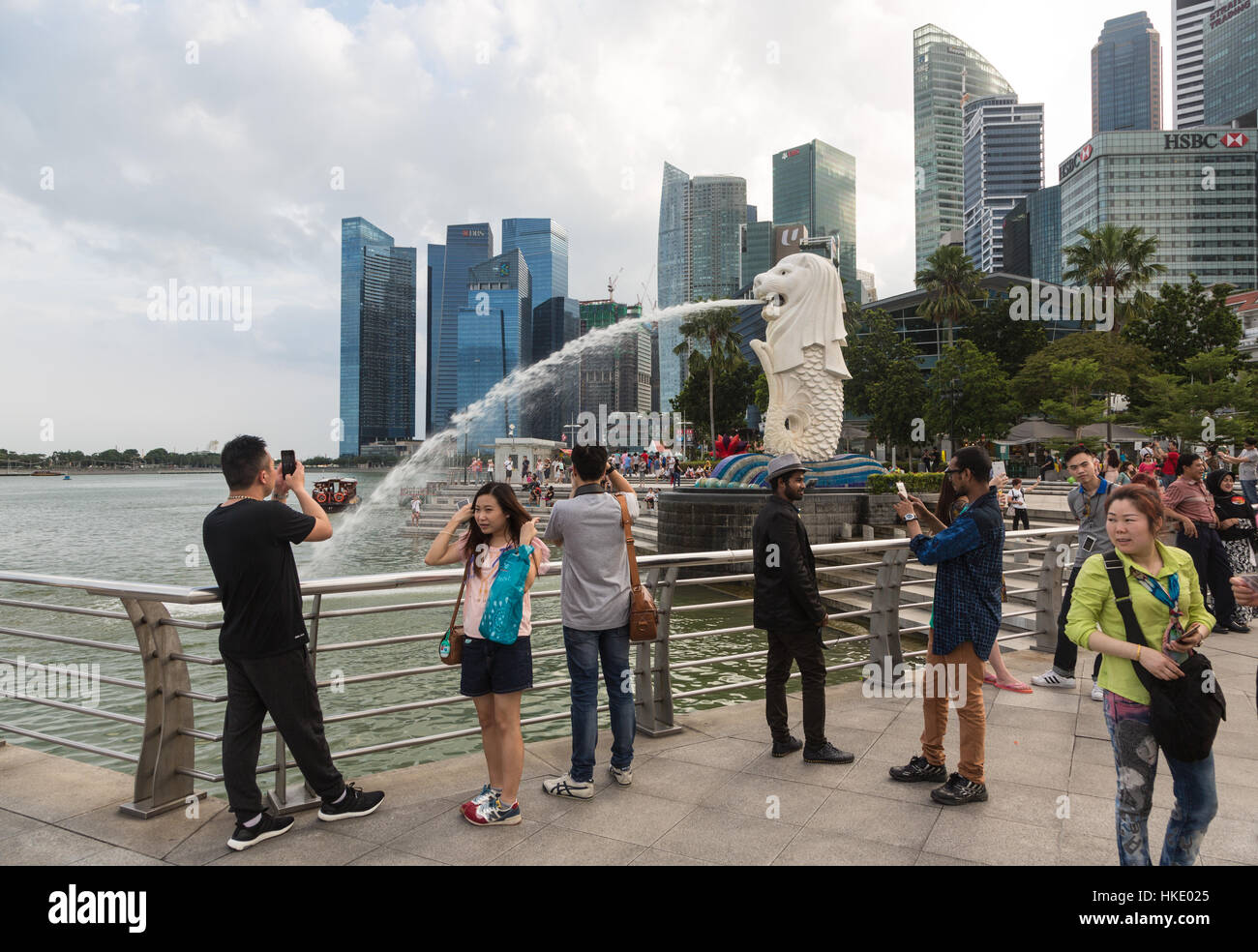 Singapur, Singapur - 22. Februar 2016: Touristen fotografieren vor der berühmten Skyline der Stadt und der Merlion Statue. Stockfoto