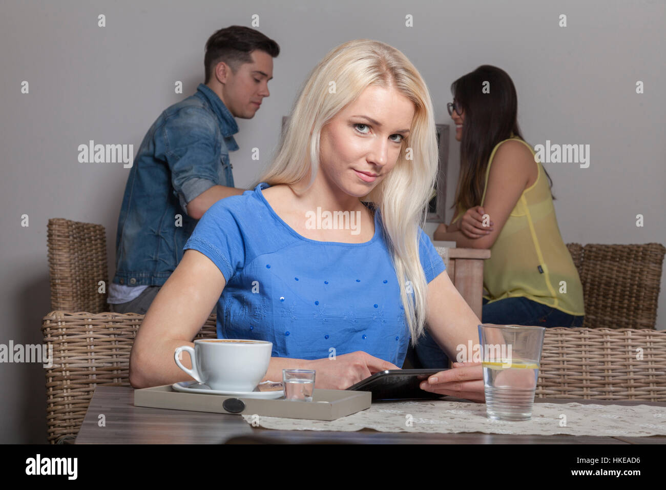 Blonde stolz Business-Frau sitzt mit Tablet im Acafeteria mit Kaffee und Wasser Stockfoto